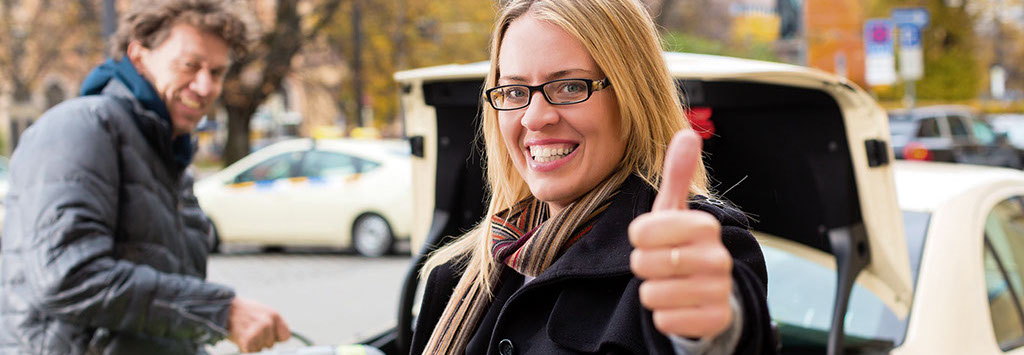 Taxifahrer hilft beim Ausladen, Frau ist vom Taxiservice begeistert